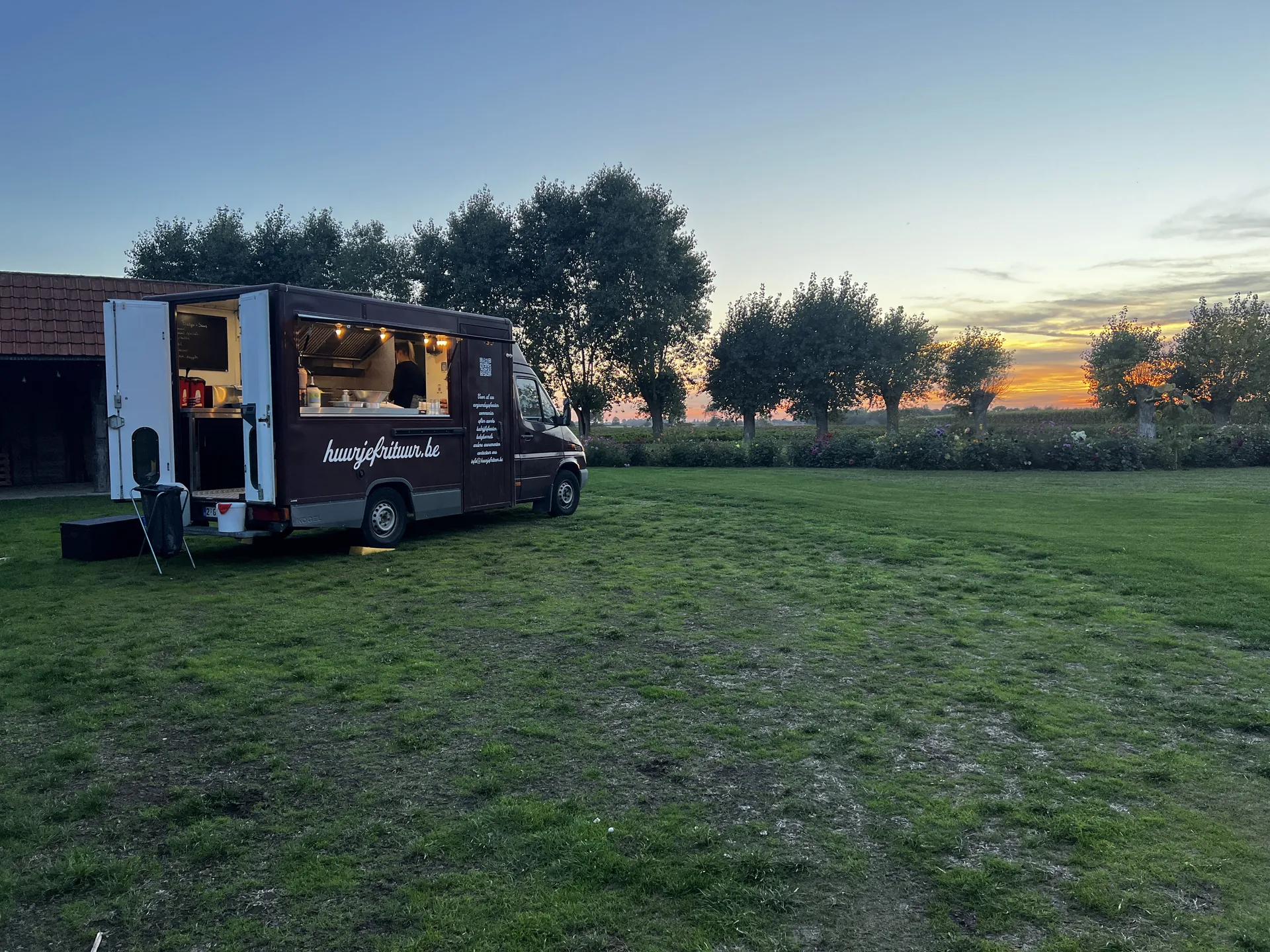 De foodtruck van Huurjefrituur op een weide bij zonsondergang